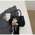 Close-up of black pebbled leather bucket bag with cute bear charm and crossbody strap - With Pendant / Black