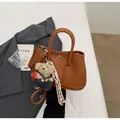 Stylish brown pebble leather handbag with cute teddy bear charm and tassel details. - With Pendant / Brown