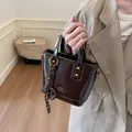 Elegant vintage dark brown gloss finish bucket bag featuring gold hardware and woven strap - With Pendant / Coffee