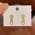 Elegant gold zipper pull stud earrings with micro-paved sparkling stones on display card - Zipper Head Design Style (E3247)