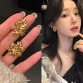 Elegant gold-tone flower stud earrings worn by an Asian model in soft indoor light - Vintage 3D Flower Stud Style (A2043 Gold) / Gold