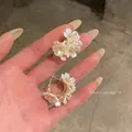 Vue détaillée d'élégantes boucles d'oreilles fleurs de jasmin blanc avec centres dorés - Ensemble de boucles d'oreilles boules de fleurs et couronnes / Or Blanc