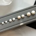 Natural freshwater white bun pearl stud earrings in various sizes on a display stand - One Pair / 3mm / Gold + White Pearl