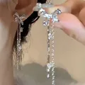 Close-up detail of silver sparkling diamond bow tassel earrings with flowing chains - Asymmetric Tassel Style (A1239)