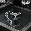 Gedetailleerde close-up van een hartvormige maansteen op een open zilveren ring. - Verstelbare ring stijl 10