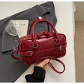 Close-up of a stylish red crossbody handbag with leather handles for daily commute. - No Pendant / Red
