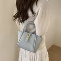 Elegante bolso de cubo en cuero texturizado azul claro con hebilla dorada y asa superior - Azul