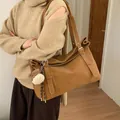 Modische braune Leder-Einkaufstasche mit großem Fassungsvermögen, getragen von Model - Mit Anhänger / Braun