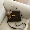 Élégant sac à main en daim marron foncé avec boucle dorée et breloque ours en peluche - Avec Pendentif / S / Café