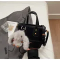 Detailweergave van een stijlvolle zwarte emmertas met een schattige grijze konijnenhanger - Met Hanger / Zwart
