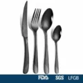 Detail of black stainless steel cutlery set with textured handles, includes knife, fork, and spoons - Black / 4 Pieces