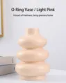 Gros plan d'un vase en céramique rose clair nordique au design unique de donut - Circle light