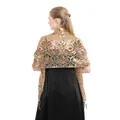 Rückansicht eines eleganten goldenen Pailletten-Schals mit Quasten zu einem schwarzen Kleid. - Gold
