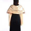 Rear view of a elegant champagne gold satin shawl wrap draped over a black evening dress - Champagne