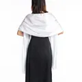 Detail view of a luxurious white satin shawl wrapped over a black evening dress back. - M / White