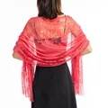 Back view of an elegant red floral lace shawl with long tassels paired with a black evening dress - Watermelon red