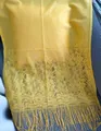 Detailed close-up view of bright yellow lace shawl featuring floral patterns and tassels - Yellow