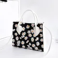 Stylish black and white daisy floral print handbag featuring white handles and strap - Daisy Style / Black