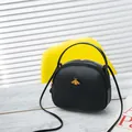 Elegant black round PU leather crossbody bag with a gold bee ornament and top handle. - Black