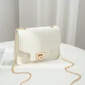 White crocodile embossed crossbody bag featuring a golden chain strap and flip lock - White