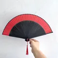 Dettaglio del ventaglio pieghevole cinese rosso e nero con una nappa rossa decorativa - Stile Piatto Tinta Unita / Lunghezza Impugnatura 21cm / Rosso