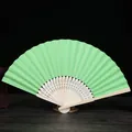 Vista detallada de un abanico de papel verde claro de 7 pulgadas con varillas de bambú. - Verde oscuro