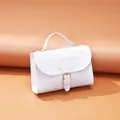 Elegant white handbag with stone texture pattern, featuring top handle and gold buckle. - White
