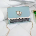 Light blue small crossbody bag with cat pearl ornament and glitter panel on white bed. - Blue (Sequined)
