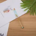 Penna gel creativa a forma di piuma dorata con ornamento azzurro su scrivania - Blu Lago Con Stampa Oro