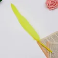 Close-up of a bright yellow feather ballpoint pen on an elegant book page background - Yellow
