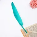 Close-up of elegant teal feather ballpoint pen on vintage paper - Cyan
