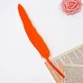 Detailed macro view of an elegant orange feather ballpoint pen on vintage book paper. - Orange