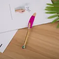 Dettaglio macro di una penna gel a piuma magenta con corpo in metallo dorato su una scrivania. - Rosa Rosso Con Stampa Oro