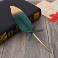 Close-up of elegant gold-sprayed green feather quill pen with a striped bow detail - Dark Green Feather