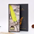 Vista detallada de un set de pluma de ave vintage amarilla en caja de regalo negra de lujo. - Amarillo
