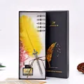 Detailed view of yellow feather quill pen set with five nibs and ink in a black gift box. - Yellow