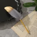 Primo piano di un'elegante penna a sfera in piuma grigia e oro su pagina di libro vintage. - Grigio