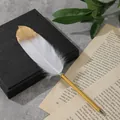 Dettaglio di penna a sfera in piuma bianca con punta dorata su pagine di libri. - Bianco
