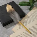 Primo piano di un elegante penna a sfera piuma con punta sfumata dorata - Grigio Originale