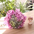 Close-up view of pink artificial hydrangea bouquet with realistic buds on wooden table - Purple