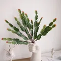 Detailed view of artificial green cactus plant with red tips in a creative white vase - Orange