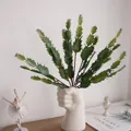 Detail view of artificial cactus plant inside a creative fist shaped white ceramic vase. - Purple