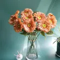 Macro shot of orange artificial gerbera flowers in a gold-rimmed glass vase - Coffee