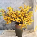 Primer plano de flores de gypsophila amarillas artificiales en un jarrón de cerámica - Naranja