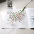 Primer plano de una rama de paniculata artificial rosa sobre una revista abierta decor - Rosa