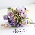Nahaufnahme eines violetten Pfingstrosen und Rosen Kunstblumenstraußes auf Buch. - Lila