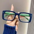 Nahaufnahme einer modischen Lesebrille mit dunkelblauem Rahmen und grünen Bügeln in der Hand - +1.00 / Blauer Rahmen Grüne Bügel
