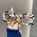 Nahaufnahme einer Retro-Lesebrille im Cat-Eye-Stil mit modischem Kuhmuster-Gestell. - +1.00 / Schwarz-weiß gepunkteter Rahmen