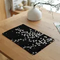 Detailopname van zwart linnen placemat met witte kersenbloesemprint op een houten tafel - Zwart Wit Kersenbloesem (7816-12)
