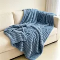 Weiche, feste, blaue Kunstfell-Kuscheldecke, die über ein modernes beiges Sofa geworfen wurde. - Blaugrün